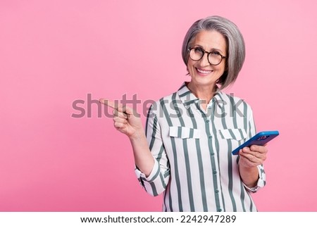Photo of shiny cheerful lady wear smart casual clothes typing modern device pointing empty space isolated pink color background