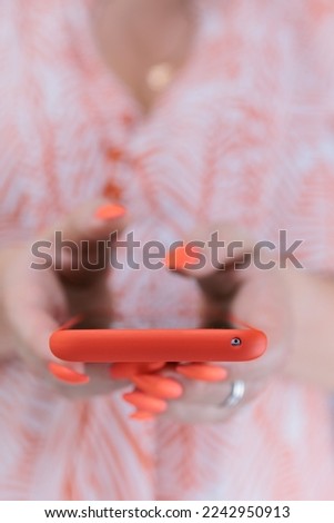 Woman's hands holding a large red neon smartphone