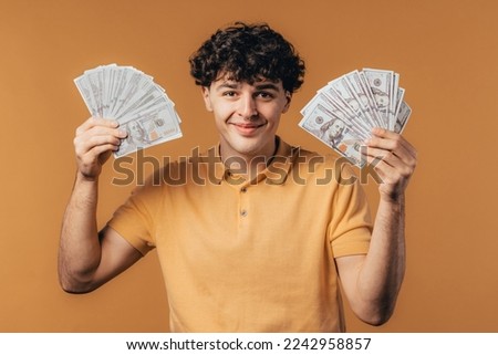 Rich excited man with cash money - USD currency dollars banknotes on yellow wall. Symbol of jackpot, gain, victory, winning the lottery. High quality photo