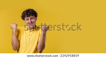 Curly man shows triumph yes YEAH gesture of victory, he achieved result, goals. Guy glad, happy, surprised excited happy lady on yellow background. Jackpot concept. High quality photo Royalty-Free Stock Photo #2242958859