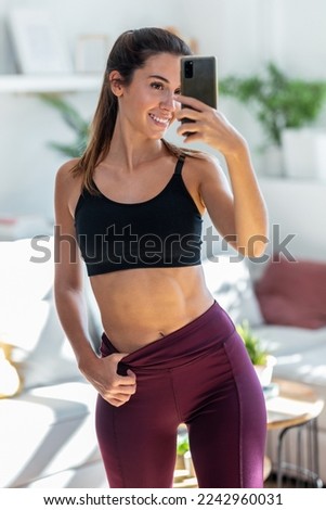 Shot of sporty woman taking photo selfie with smartphone in mirror at home.