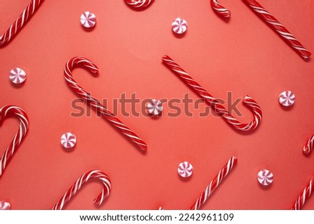 Candy canes and striped candies pattern on red background. Christmas or New year card. Selective focus.