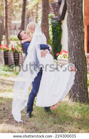 groom holds his bride in his arms