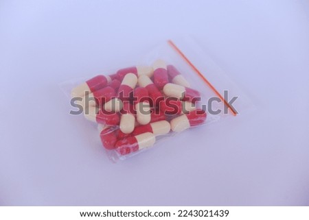 Red and white capsule pills in a clear plastic package