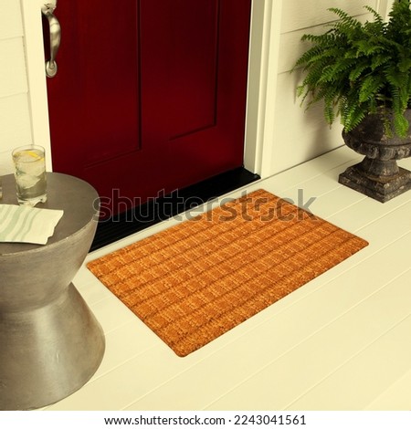Designer Welcome Entry Doormat Placed on Floor Outside Entry Door with Plants and lemon ice drink