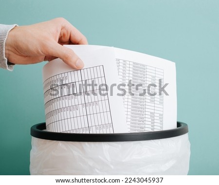 Worker throwing away documents reports bills in trash can, close-up of hand and sheets of paper. Royalty-Free Stock Photo #2243045937
