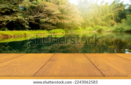 Beautiful wooden floor and blur lake or river background in nature with grass field.