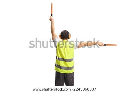 Rear view shot of an aircraft marshaller signalling with wands isolated on white background Royalty-Free Stock Photo #2243068307