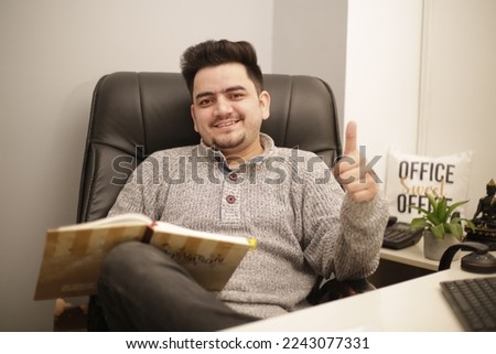 A young employee is showing thumbs  up sign and smiling.