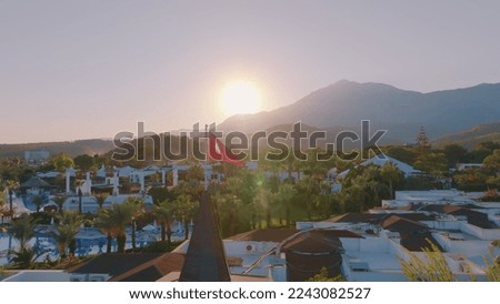 Turkish flag at sunset against the backdrop of the hotel. Swimming pool and palm trees. Mountain. Photography. High quality photo