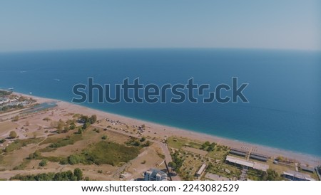 Top view of the coastline. Sea and sandy beach. Houses and hotels by the sea. Sun loungers and umbrellas on the beach. High quality photo