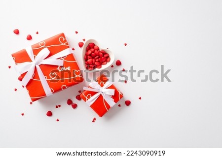 Valentine's Day concept. Top view photo of red gift boxes with ribbon bows and heart shaped saucer with sprinkles on isolated white background