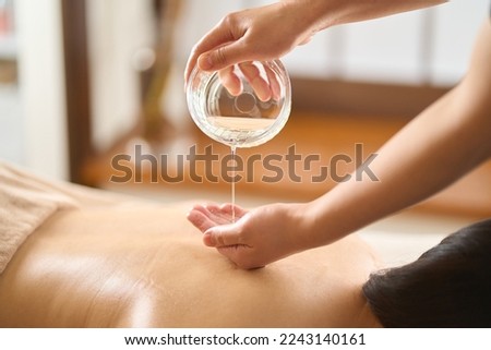 Esthetician dripping massage oil at beauty salon Royalty-Free Stock Photo #2243140161