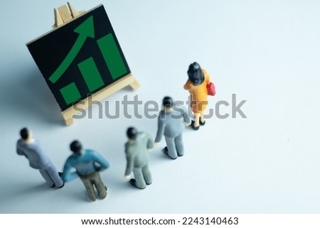 Group of businesspeople looking at a rising chart on a chalkboard. Perfect for themes related to growth, progress, success. Illustrates concepts such as business strategy, planning, development. Royalty-Free Stock Photo #2243140463