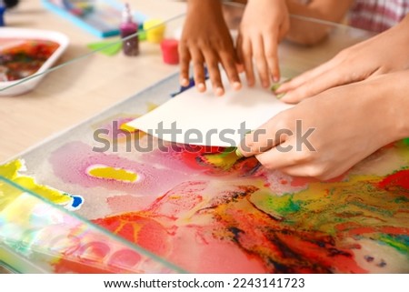 Little girls with teacher marbling paper in workshop for Ebru painting, closeup Royalty-Free Stock Photo #2243141723