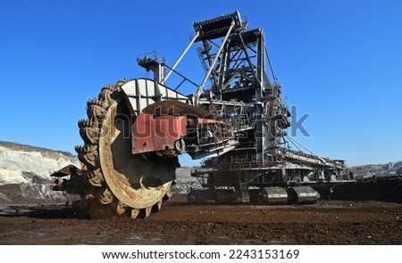 Bucket-wheel excavator during excavation at the surface mine. Huge excavator on open pit mine. Royalty-Free Stock Photo #2243153169
