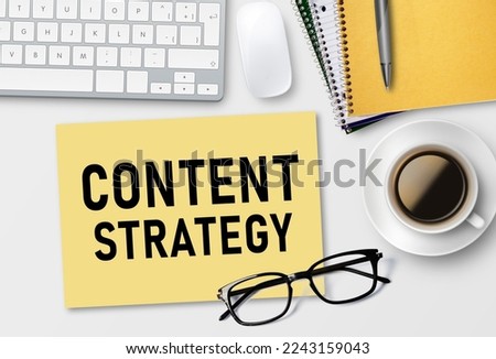 CONTENT STRATEGY text on notebook and laptop keyboard with coffee cup on white table background.