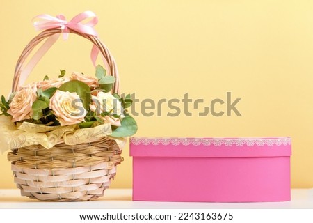 Valentine's day, mother's day, birthday. Flowers in a basket and a pink box with a gift on the table. still life space