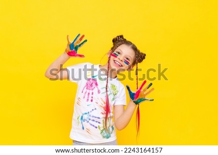 Art drawing for children. A little girl on a yellow background with her hands stained in paint.