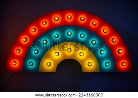 Rainbow wave art piece with light bulbs and rings of red, blue, and yellow
