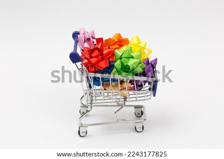Shopping for gifts. Shopping trolley filled with colorful gift wrap decorations isolated on white background. Horizontal close-up. Empty copy space for text message.