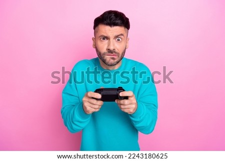 Photo of young fifa player man wear blue stylish sweater hold new gamepad nervous playing try win last match isolated on pink color background
