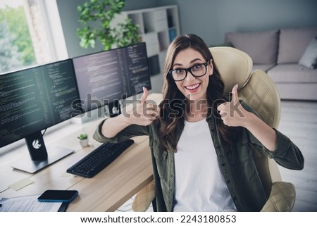 Photo of smiling excited lady coder wear spectacles showing two thumbs up indoors workplace workshop