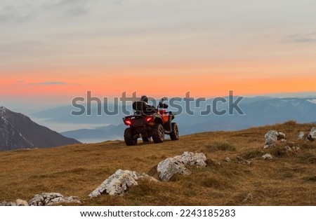 A rider riding quad bike atv off road on the mountain at sunset adventure travel.