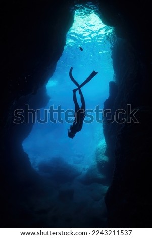 silhouette of free diver woman freediving in cave. Royalty-Free Stock Photo #2243211537