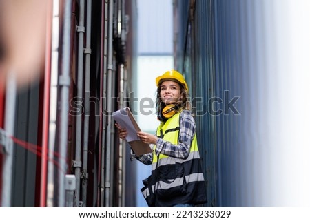 A female foreman works to supervise the loading of containers from a cargo ship for export and import. industrial shipping containers, cargo ships. Global Logistics Transport Royalty-Free Stock Photo #2243233029