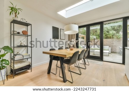 a dining room with wood flooring and glass doors that open to the backyard patio, which is surrounded by trees