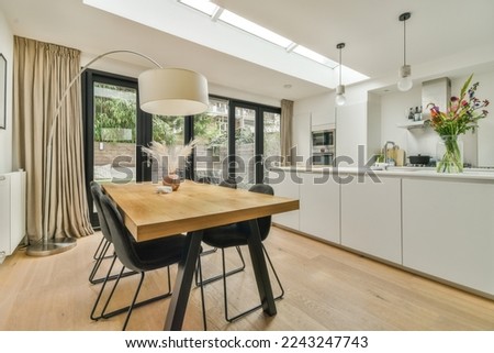 a dining room with wood flooring and skylights above the kitchen area in an open - plan living space Royalty-Free Stock Photo #2243247743