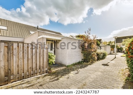 a backyard area with a wooden fence and white brick house in the photo is taken from the ground to the street