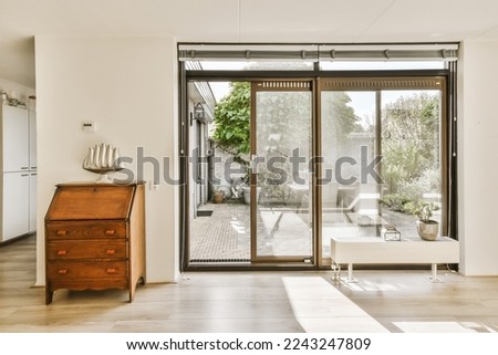 a living room with sliding glass doors that open up to the patio and backyard area in the house is white Royalty-Free Stock Photo #2243247809