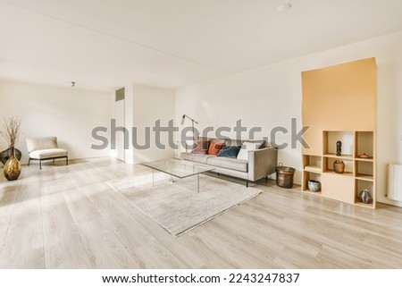 a living room with wood flooring and white walls, including a glass coffee table on the right hand side Royalty-Free Stock Photo #2243247837