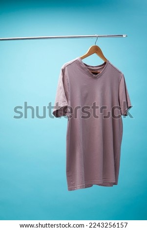 Purple t-shirt  hanging on a hanger isolated on blue background.