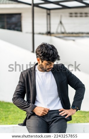 A bearded young man doing a pose with his white shirt with suit as the outer on the outdoor, mockup white blank shirt