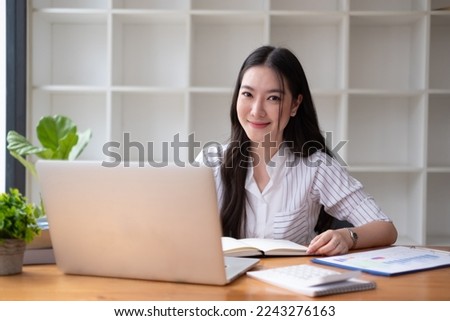 Young beautiful asian businesswoman working on tablet with happiness while sitting at the table in modern office room.