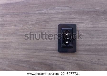 Black socket in MDF panel with wood texture.