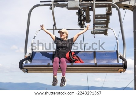 Young women sit on the Chairlift. Concept of a summer vacation in the mountains.