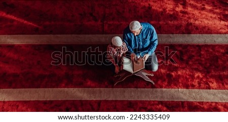 Muslim prayer father and son in mosque praying and reading holly book Quran together islamic education concept Royalty-Free Stock Photo #2243335409