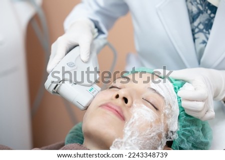 Beautician procedure by electric device,Ultrasound therapy treatment for skin tightening in aesthetic clinic. Royalty-Free Stock Photo #2243348739
