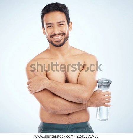 Man, fitness and water bottle in studio portrait with smile, health or wellness exercise by blue background. Model, shirtless or water for self care, self love or body positivity by studio backdrop Royalty-Free Stock Photo #2243391933