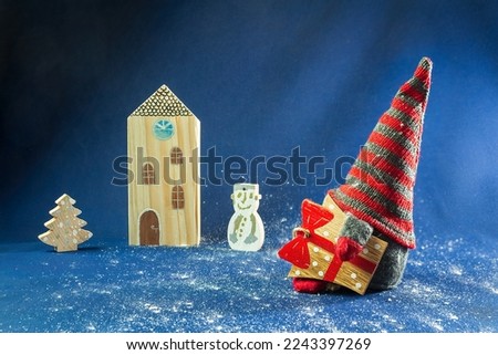 Christmas decoration elf, dwarf take gift to his building with snowman and christmas tree. Holiday background scene