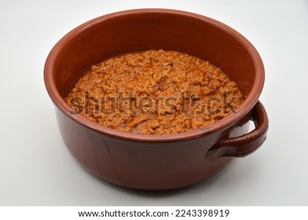 Italian bolognese ragu in a crock pot, isolated on white background. Beef and pork loin ragu. Delicious comfort healthy food.
