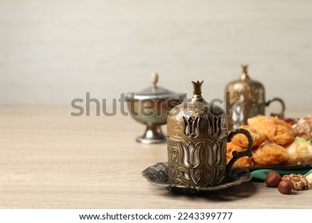 Tea, baklava dessert and nuts served in vintage tea set on wooden table, space for text