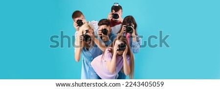 Group of young photographers on light blue background
