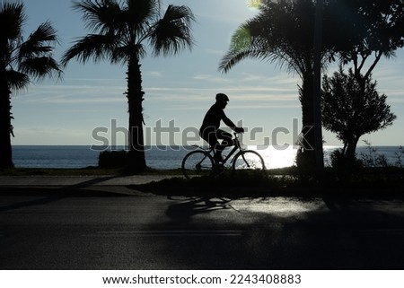 silhouette of a Man riding a bicycle against the backdrop of a sea sunset. The concept of nature and beauty. Orange sunset. Silhouette at sunset. High quality photo