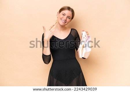 Young pretty blonde woman practicing ballet isolated on beige background giving a thumbs up gesture