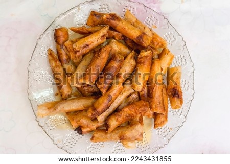 Deep fried lumpia served on a glass platter.